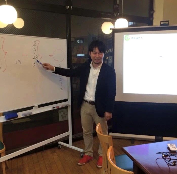 ホワイトボードを使い業務の数字を整理しながら説明する株式会社グローカルワークス代表 田中裕一郎
